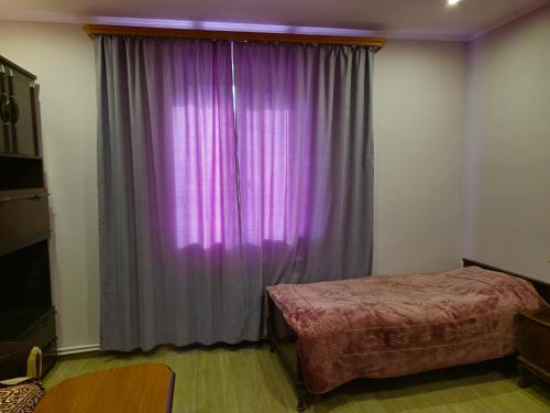 a bedroom with a purple curtain and a bed at Гостевой дом Гарни in Garni