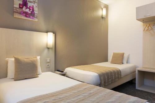 a room with two beds in a hotel room at Comfort Hotel Orléans Olivet in Olivet