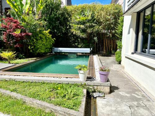 - une piscine dans une cour avec deux plantes en pot dans l'établissement Villa Rosa65 - Piscine extérieure - Salle de sport - Sauna privé, à Bagnères-de-Bigorre