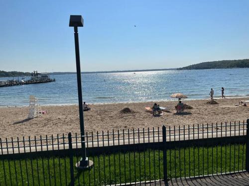 a beach with people on the sand and water at 515Escape - Near downtown, private backyard, firepit, bbq, fun! in Lake Geneva