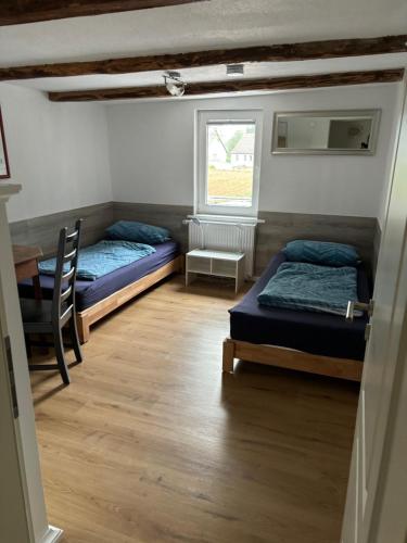 a room with two beds and a table and a window at Ferienwohnung im Hooptal in Negenborn