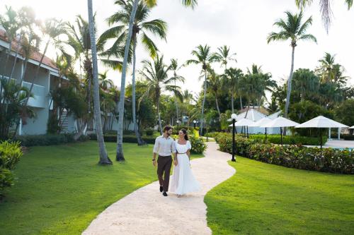 a bride and groom walking down a walkway at Wyndham Alltra Samana All Inclusive Resort in Las Galeras