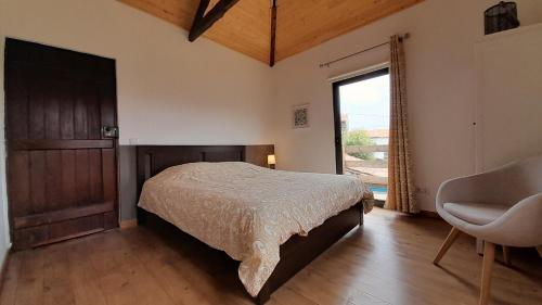 une chambre avec un lit, une chaise et une fenêtre dans l'établissement Casa Laranjeira, à Vale de Cameiro