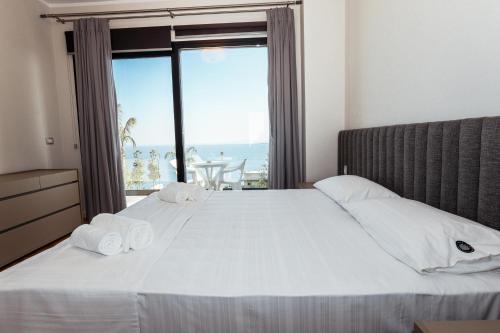 a bedroom with a large white bed with a large window at Villa White Pearl in Palasë