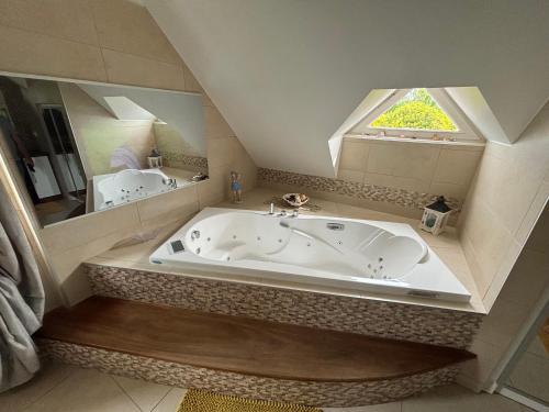 a large bath tub in a bathroom with a window at La Villa Boutrois in Isigny-sur-Mer