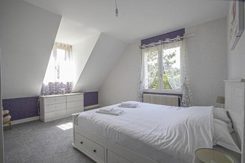 a bedroom with a large bed and two windows at La Villa Boutrois in Isigny-sur-Mer