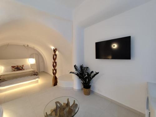 a white room with a table and a tv on a wall at The Magic Luxury Cave Suites in Vóthon