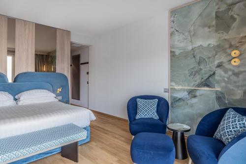 a bedroom with a bed and two blue chairs at Hotel Val Di Sogno - Adults Only in Malcesine