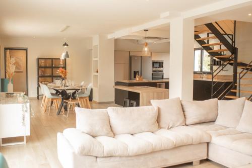 a living room and kitchen with a white couch at Les Villas Chamontines - La Villa des Chênes in Labeaume