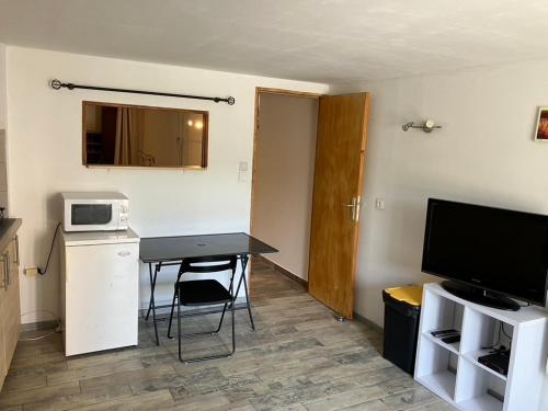 a small kitchen with a table and a microwave at appartement deux pieces in Notre-Dame-de-Londres