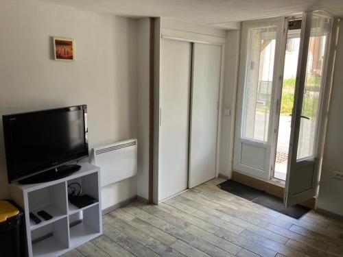 a living room with a flat screen tv and a door at appartement deux pieces in Notre-Dame-de-Londres