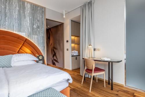 a bedroom with a bed and a desk and a table at Hotel Val Di Sogno - Adults Only in Malcesine