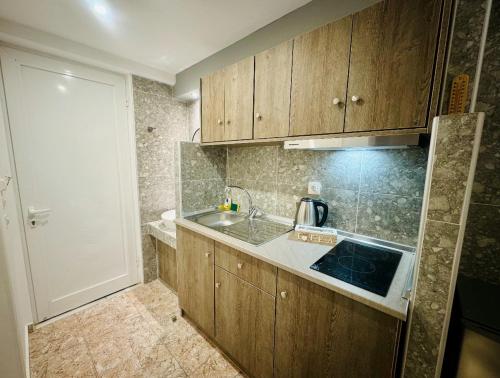 a small kitchen with wooden cabinets and a sink at Peter's Place Studios & Suites in Faliraki