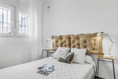 a white bedroom with a bed with a large headboard at La Casita Blanca in Barbate