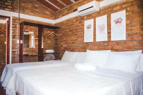 a bedroom with a white bed in a brick wall at Hotel Alvorada in Garanhuns