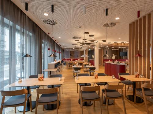a restaurant with tables and chairs and windows at Holiday Inn Express Heilbronn by IHG in Heilbronn