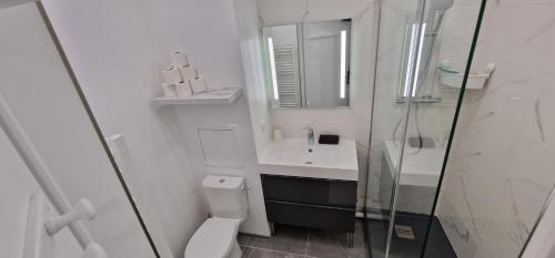 une salle de bain blanche avec des toilettes et un lavabo dans l'établissement Studio Disneyland RER 4 pers, à Montévrain