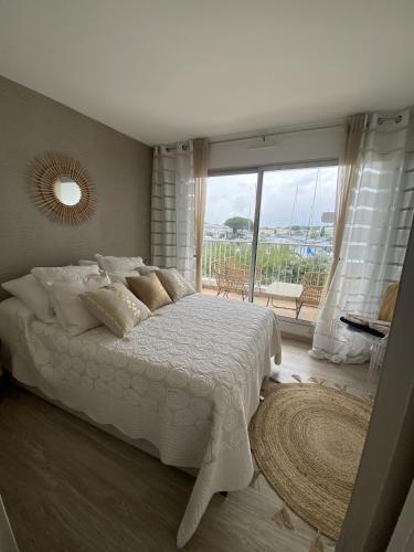 une chambre avec un lit blanc et une grande fenêtre dans l'établissement Sol-y-Days Santa Maria vue sur les marinas, au Grau-du-Roi