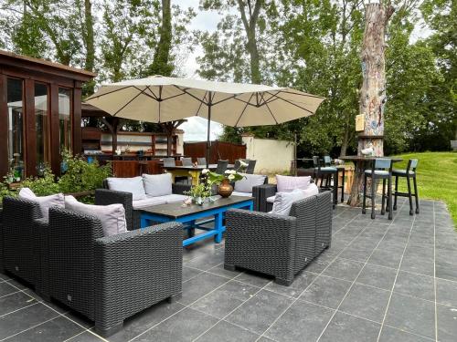 a patio with wicker chairs and a table with an umbrella at Grande Maison familiale in Maillebois