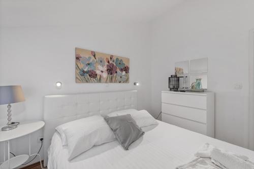 a white bedroom with a bed and a painting on the wall at Apartments Petrina in Sveti Filip i Jakov