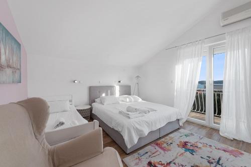 biała sypialnia z łóżkiem, krzesłem i oknem w obiekcie Apartments Petrina w mieście Sveti Filip i Jakov