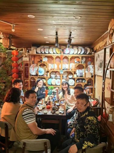 a group of people sitting around a table in a room at Lijiang Old Town Meiliju View Inn in Lijiang