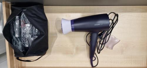 un sèche-cheveux noir sur une table avec un sac dans l'établissement Studio Disneyland RER 4 pers, à Montévrain