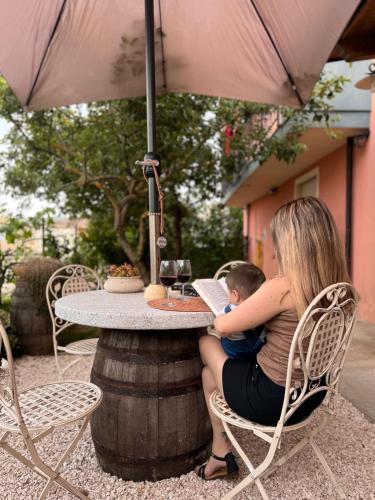 a woman holding a baby sitting in a chair under an umbrella at B&B La Baita "monolocale ad uso esclusivo" in Fonni