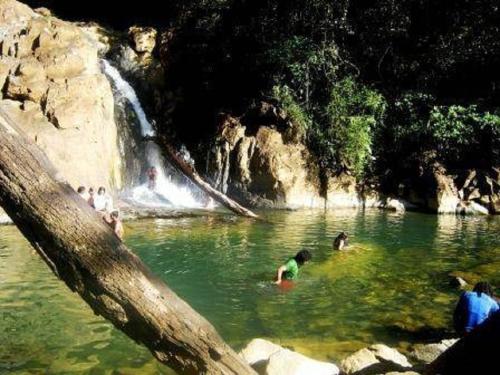 a group of people swimming in a river with a waterfall at Casa Grande Retiro para grupos in Cerro Azul