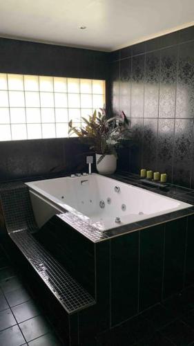 a bath tub in a black bathroom with a plant at Villa a Hovås con molti comfort in Hovås