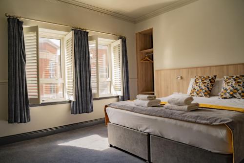 a bedroom with a large bed with two windows at The Old Quarter Townhouse in Limerick