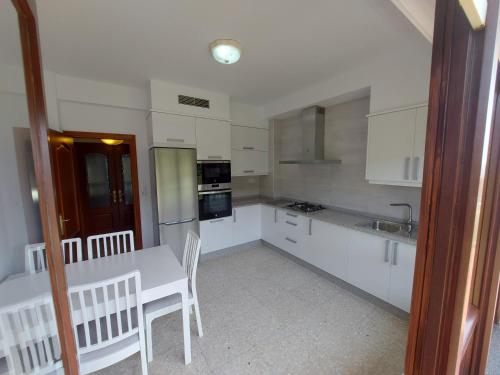 a kitchen with white cabinets and a table and chairs at Bahia de Ezaro, Costa da Morte in Dumbría