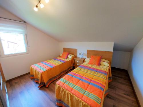two beds in a small room with a window at Bahia de Ezaro, Costa da Morte in Dumbría