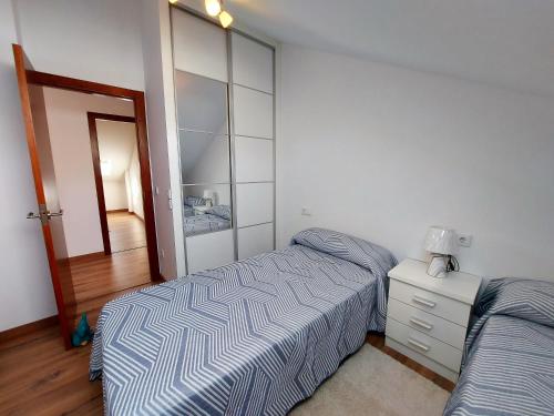 a bedroom with a bed and a dresser and a mirror at Bahia de Ezaro, Costa da Morte in Dumbría