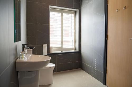 a bathroom with a sink and a toilet and a window at The Old Quarter Townhouse in Limerick