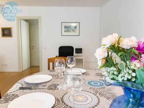 a table with wine glasses and a vase of flowers at Cattedrale 5 Tirabora Short Rent in Trieste