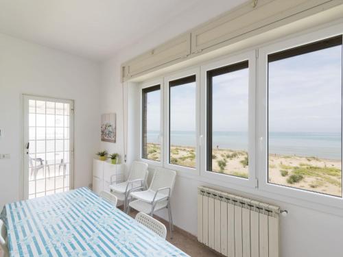 Habitación blanca con ventanas, mesa y sillas en Apartment Rome's Beach House 1 by Interhome, en Torvaianica