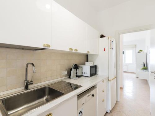 cocina con armarios blancos, fregadero y nevera en Apartment Rome's Beach House 1 by Interhome, en Torvaianica