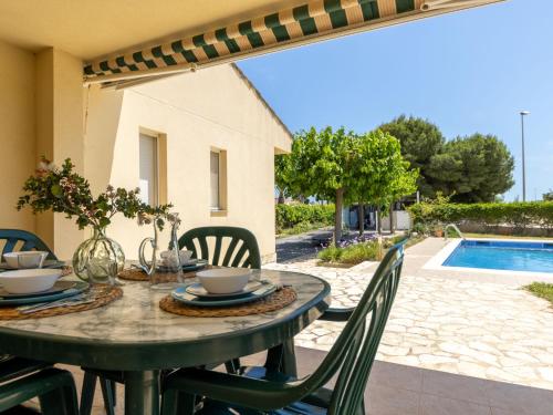 a table and chairs with a table and a pool at Villa Imma by Interhome in L'Eucaliptus