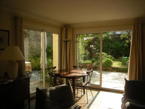 d'un salon avec une table, des chaises et une porte coulissante en verre. dans l'établissement Maison centre ville avec jardin, à Concarneau