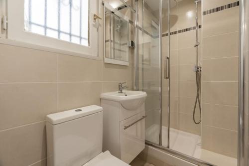 une salle de bain blanche avec toilettes et douche dans l'établissement Appartement cosy canal Saint Martin, à Paris