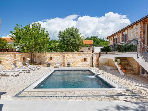 a pool in a courtyard with chairs and a building at Holiday Home Villa Frane by Interhome in Maslenica
