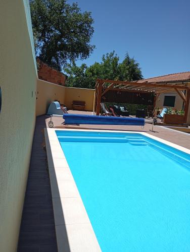 a large blue swimming pool next to a house at Casa da Floresta in Santiago da Guarda