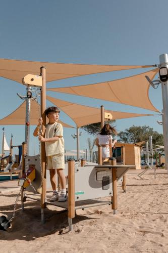 a young boy is standing on a play equipment on the beach at Club Hotel Aguamarina in Arenal d'en Castell