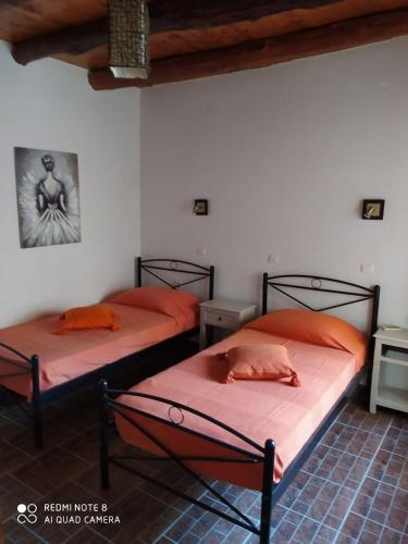 two beds with orange pillows in a room at Charmante maison crétoise à Embrosneros in Embrósneros