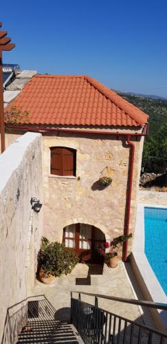 a building with a tile roof next to a swimming pool at Charmante maison crétoise à Embrosneros in Embrósneros