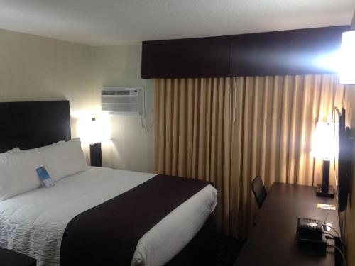 a hotel room with a bed and a desk with two lamps at Days Inn by Wyndham Sylvan Lake in Sylvan Lake