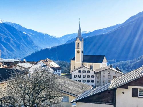 a church with a clock tower in a town with mountains at Apartment Panorama da muntognas by Interhome in Trin