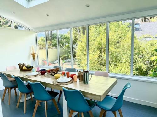 une salle à manger avec une table, des chaises et des fenêtres dans l'établissement Villa Pomponnette, à La Baule