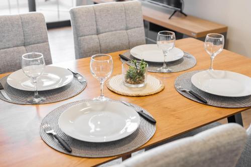 Una mesa de madera con platos y copas de vino encima. en Excelente Depto en Las Lomas, en Asunción
